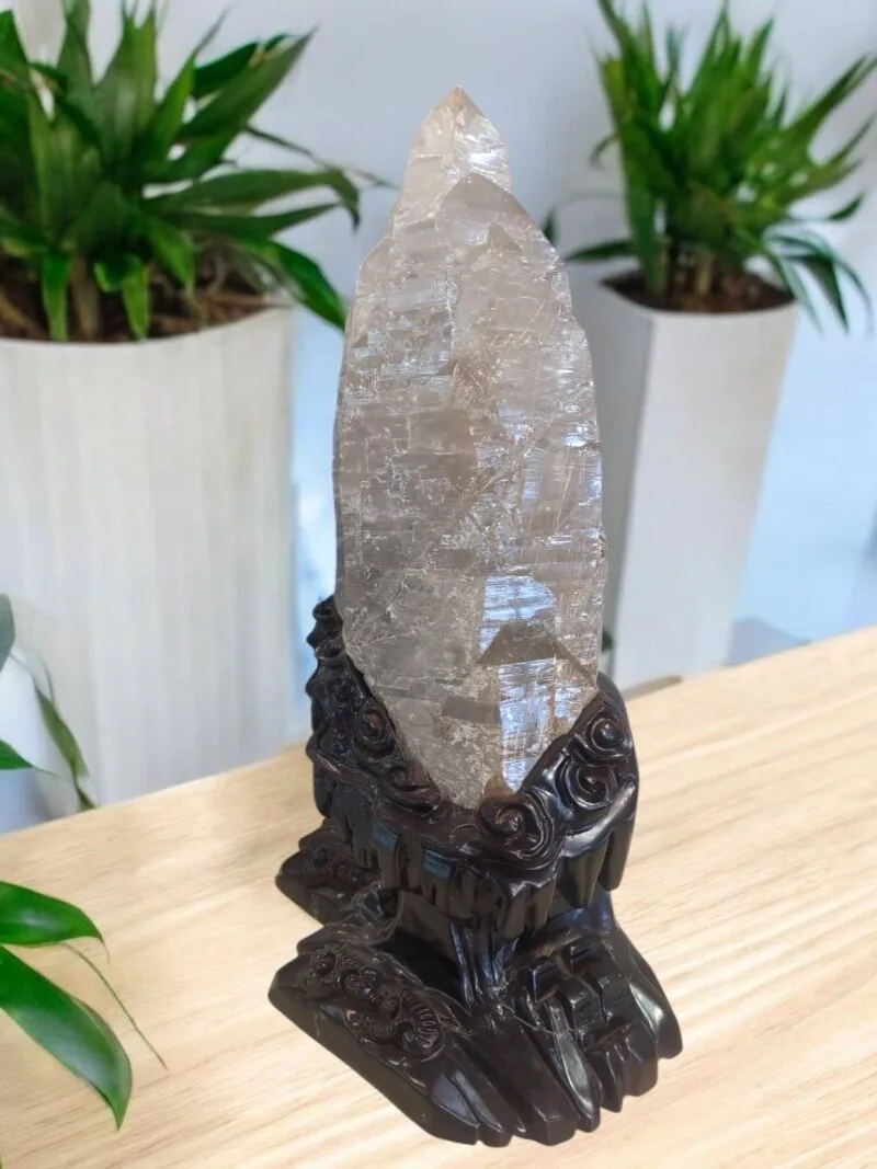 A huge clear quartz shard with a decorated wooden base.