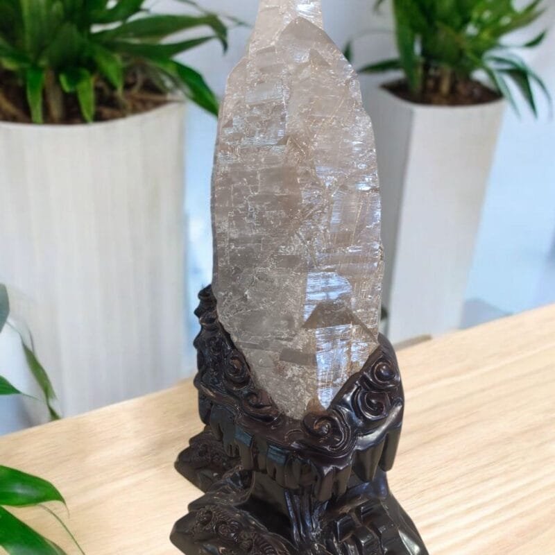 A huge clear quartz shard with a decorated wooden base.